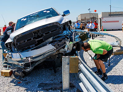 People checking out a damaged truck at a previous Midwest Roadside Safety Facility test crash