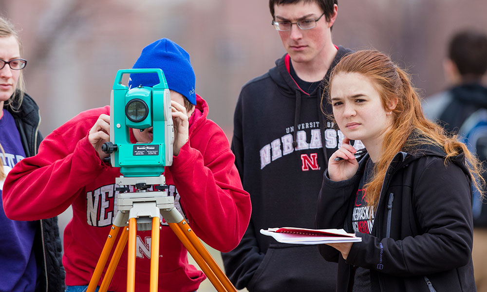 Civil Engineering Students surveying and looking through a tripod.