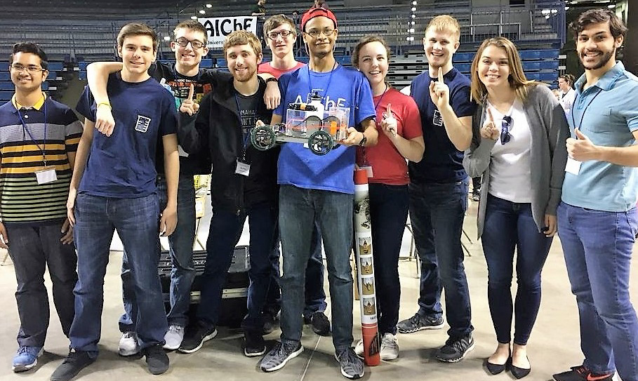 Group of students holding a trophy for a competition they placed first in. 