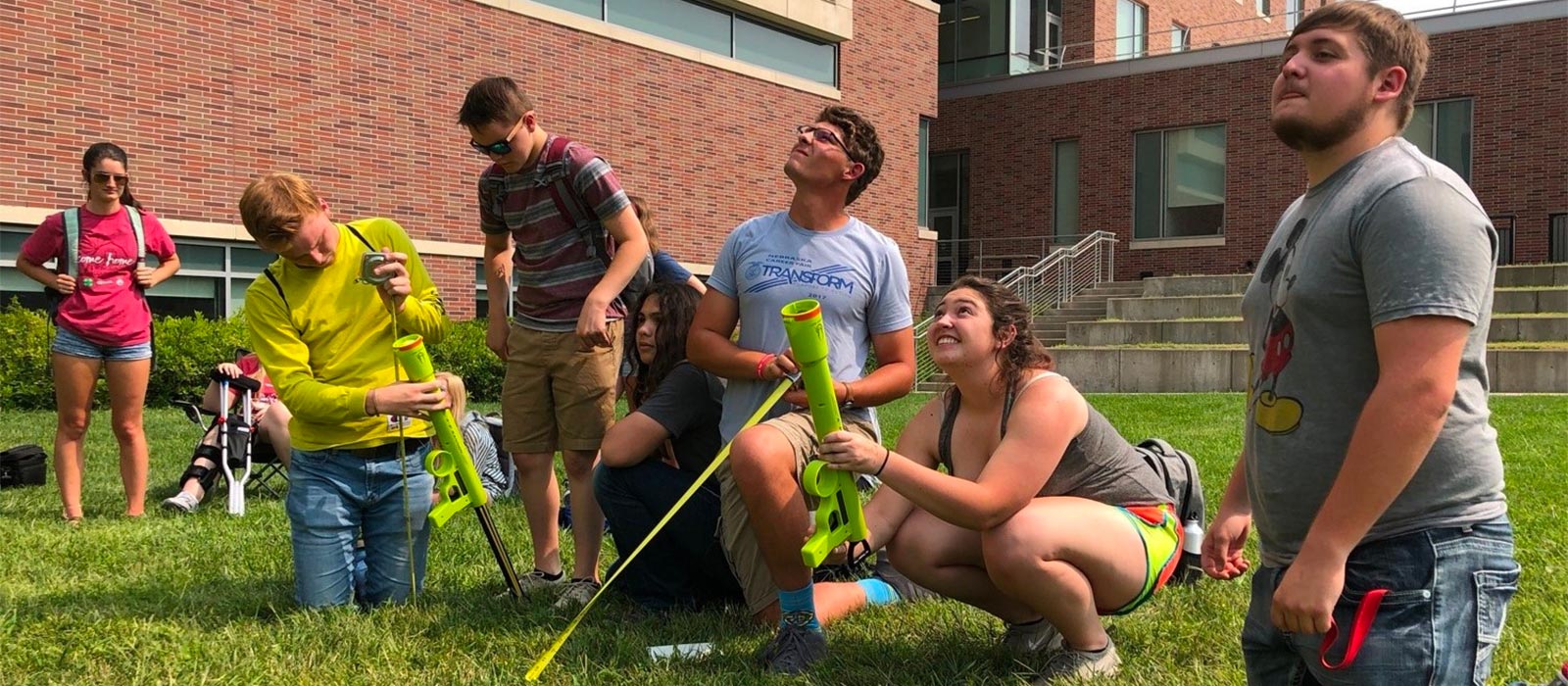 A group of engineering students observe as they launch a tennis ball into the sky with a launcher