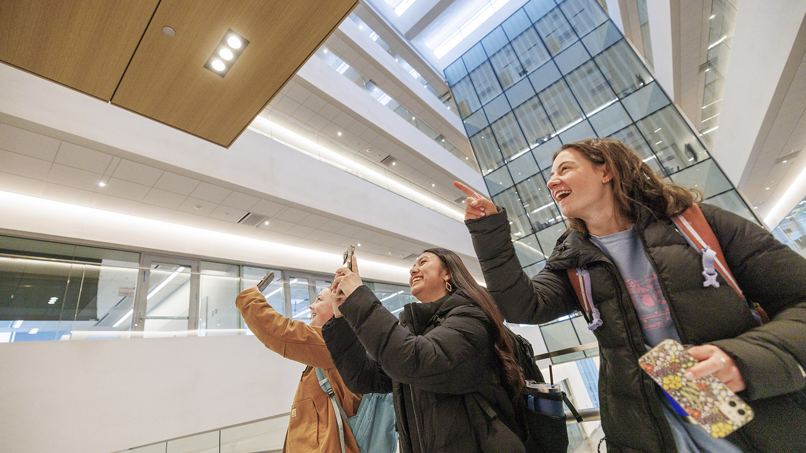 three women take photos in the new Kiewit Hall on January 22, 2024