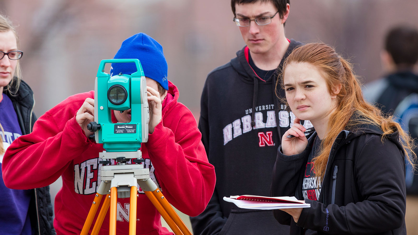 Civil students looking through a surveying instrument with other students looking on. 