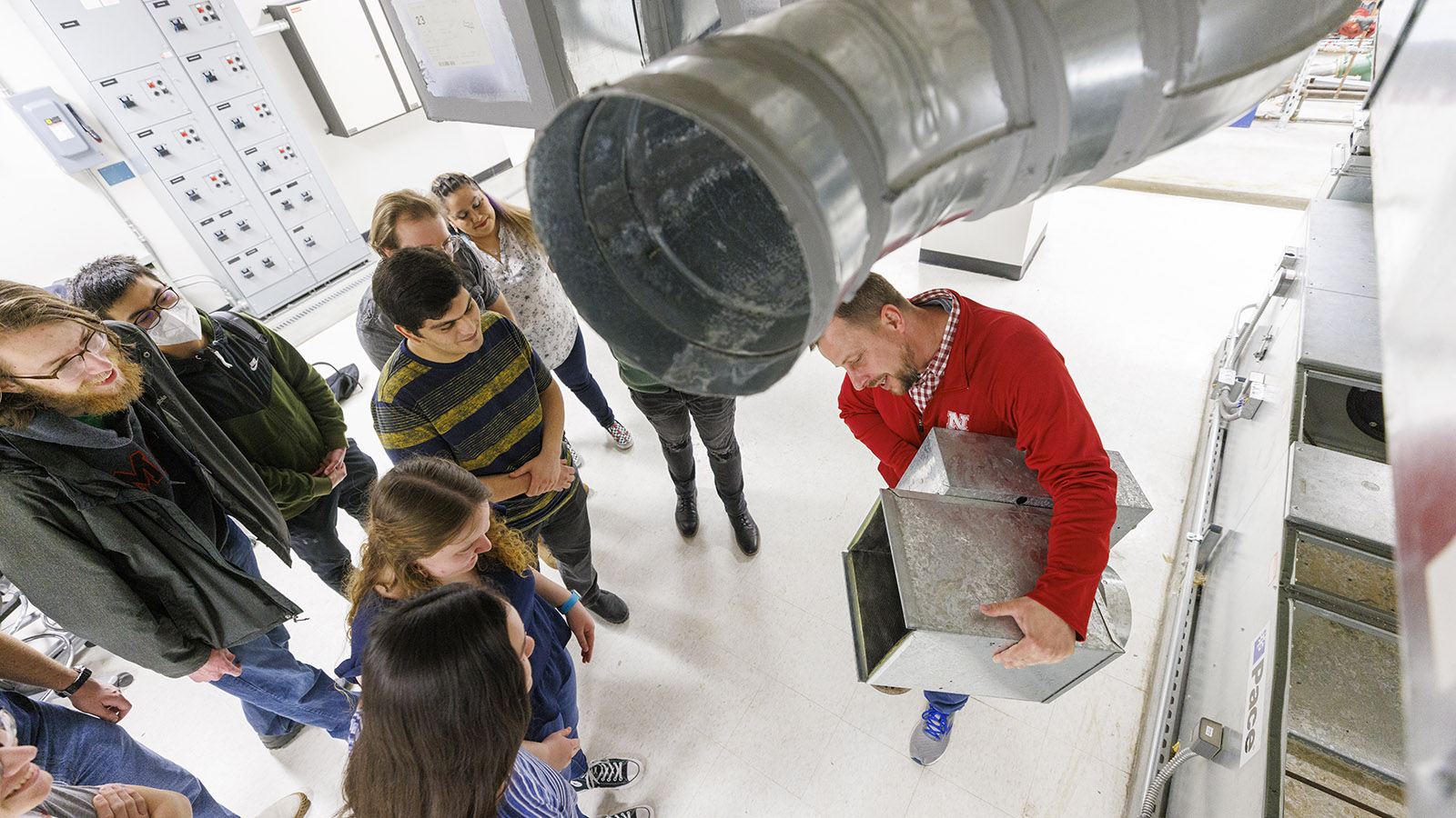 Students and faculty member looking at an HVAC system