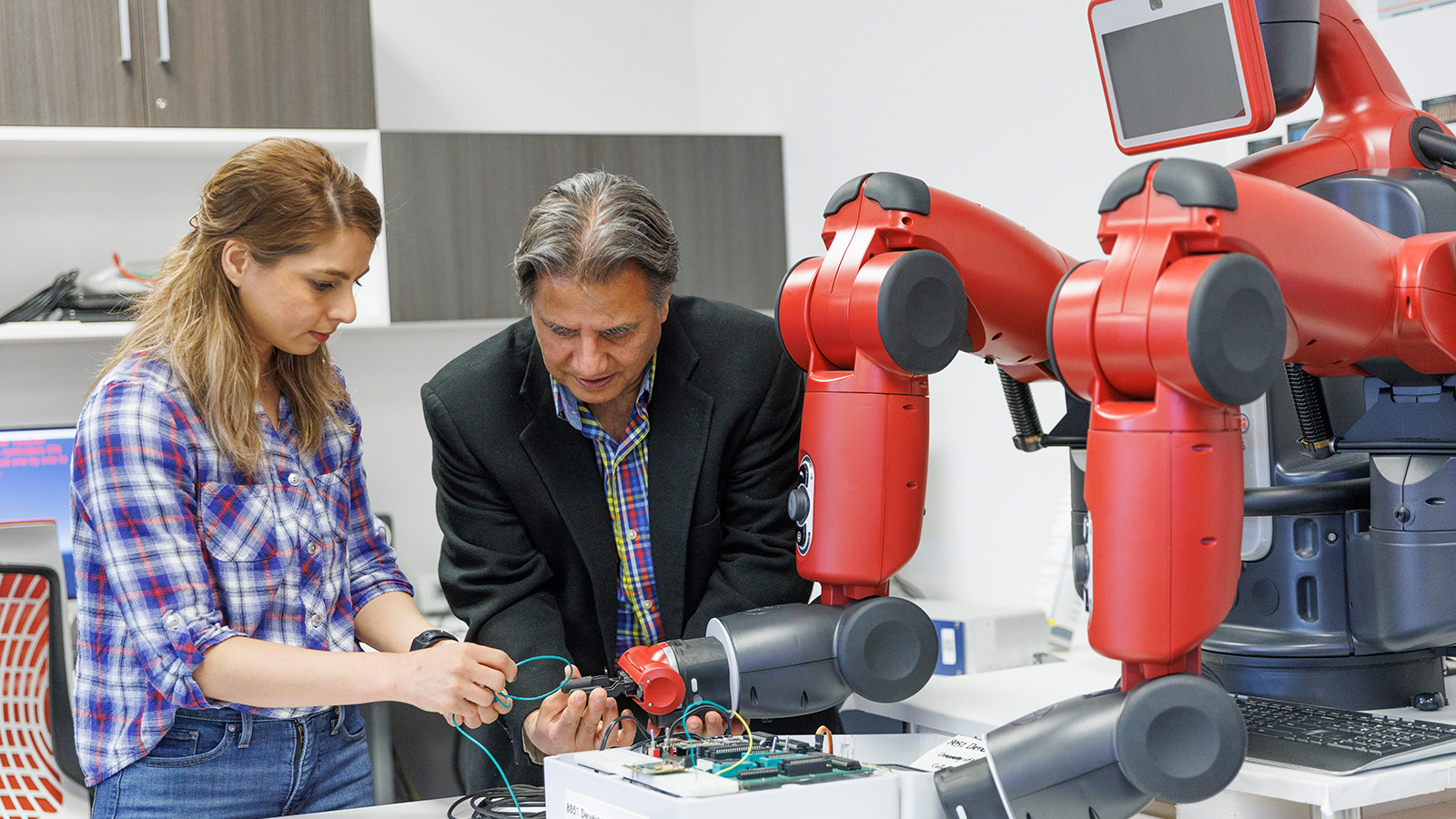 Professor and student working together with a robot in a lab.
