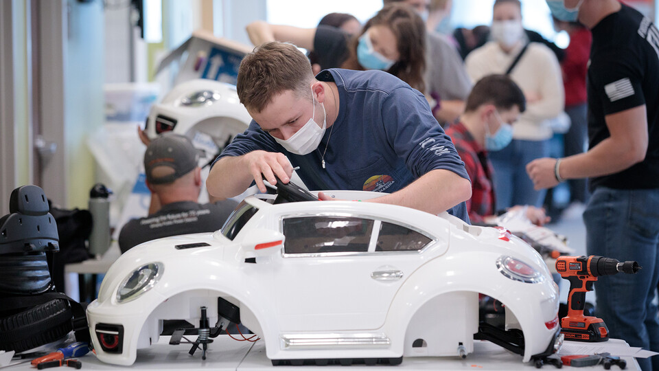 Ethan Bowles, a senior in biological systems engineering, makes an adjustment to the steering wheel in an electric car during the GoBabyGo! build on April 2. Bowles was among seven Huskers to assist with the project. This was his third time volunteering for the event. (Kent Sievers / UNMC)
