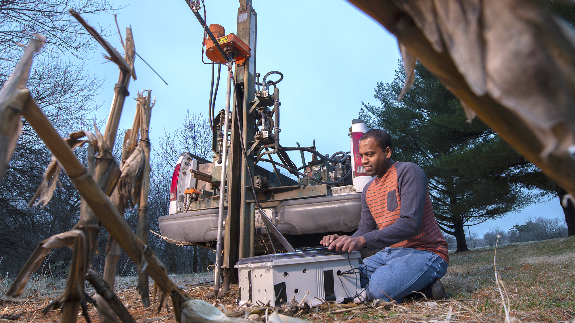 Nuwan Wijewardane, postdoctoral researcher in biological systems engineering, prepares to hydraulically plunge a penetrometer prototype into soil. (Greg Nathan / University Communication)