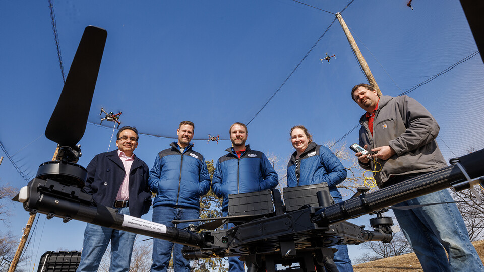 (From left) Francisco Muñoz-Arriola, Justin Bradley, Carrick Detweiler, Brittany Duncan and Trenton Franz pose among unmanned aerial vehicles at the NIMBUS outdoor flying area on Nebraska Innovation Campus. The teams have earned two grants to push the boundaries of what robots can do and expand human understanding of how climate change is impacting agricultural, aquatic and wildland systems. (Craig Chandler / University Communication and Marketing)