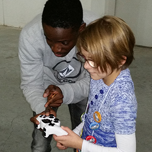 Daryl Dodoo, a junior computer engineering major, explains how to work the controls of a robot to 9-year-old Mia Vogel during the Nebraska Robotics Expo on Feb. 21 at the Strategic Air Command Museum.