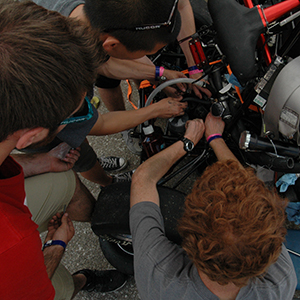 Husker Motorsports team members work to repair the car on June 19 after its clutch pin was sheared.