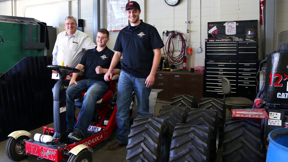 Roger Hoy (from left), Caleb Lindhorst and Luke Prosser show off a tractor designed by students for a 2014 engineering competition. Lindhorst was involved in a December 2013 auto accident and support from Hoy and Prosser has helped him return to classes on campus. For his work supporting Lindhorst and other students, Hoy has received the James V. Griesen Exemplary Service to Students Award.