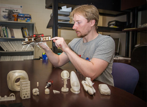 University of Nebraska-Lincoln mechanical engineering graduate student Matthew Mahlin displays some objects made by a 3D printer in the lab.