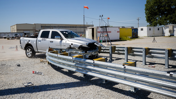 A truck crashes into a bull-nose barrier being tested for use in medians to protect cars from overpass columns. The front wood pylons are designed to shear off easily along with several metal ones. The shearing allows the energy of the crash to be transferred into the ground. Cables in the guard rails are designed to keep the car or truck captive and not let it deflect back into traffic.