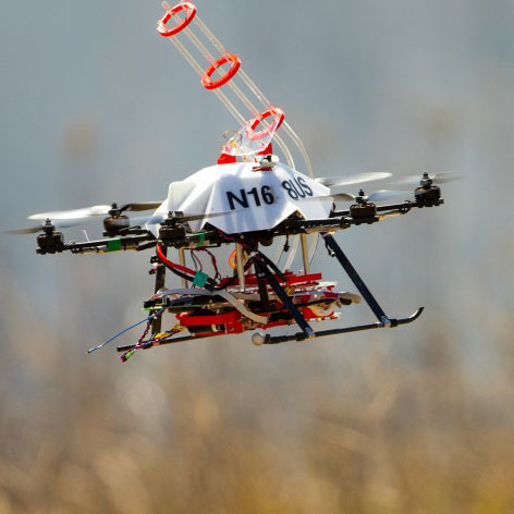 A UNL-designed drone returns to the side of a burn area for a reload of fireballs and the chemical to make them burn. The balls are carried aloft in the tubular structure atop the drone. The ball carries a chemical powder and, while airborne, the drone injects a second chemical. The drone then drops the ball and it bursts into flames within 60 seconds. (Craig Chandler / University Communications)