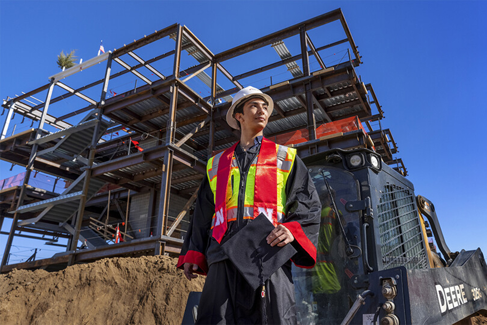Yajyoo Shrestha, a graduating senior in civil engineering, stands before the construction site of the new College of Education and Human Sciences building on City Campus. (Craig Chandler / University Communication)