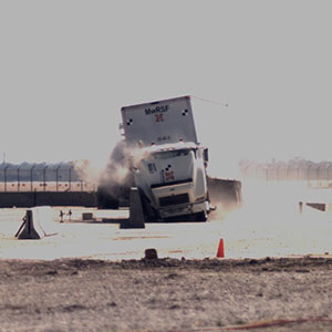 An 80,000-pound tractor-trailer crashes during a test of a concrete barrier on April 13 at the Midwest Roadside Safety Facility.