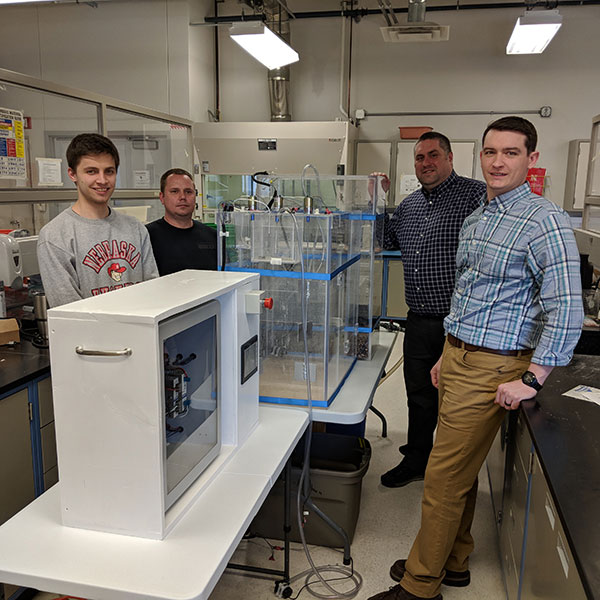 As a unique collaboration between civil engineering and electrical and computer engineering departments - students John Strudl (left), Derek Nelsen (second from left), Jacob Eckstrom (right) and Isaac Knutson (not pictured) and senior design instructor George Hunt (second from right), assistant professor of practice in civil engineering - created a working model of a water treatment plant that could be used for K-12 and general public outreach.