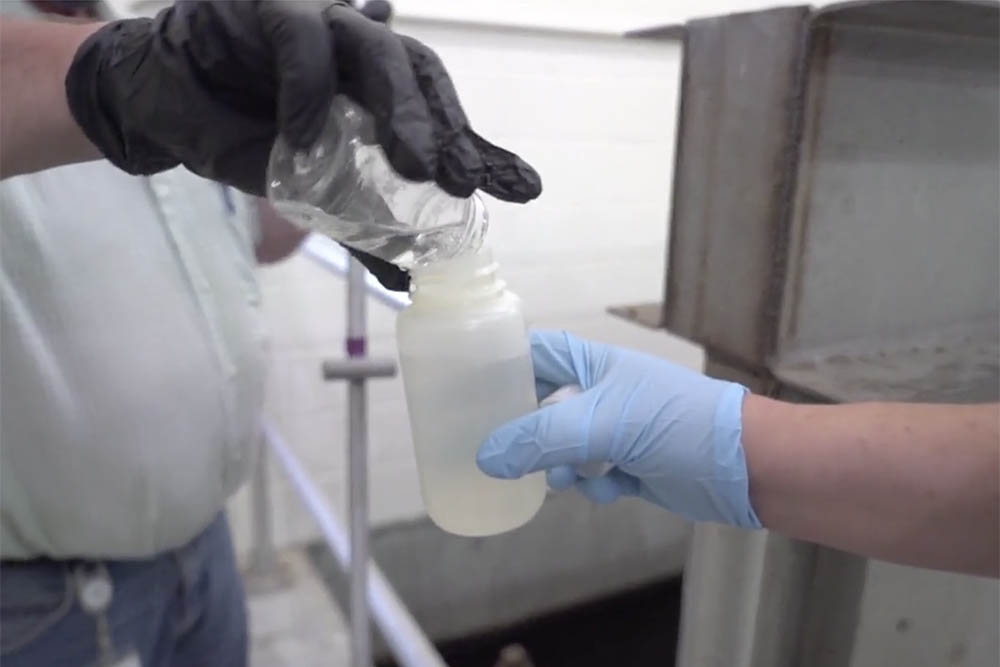 An employee at Lincoln's Teresa Street treatment facility pours a sample of outgoing treated water into a bottle held by Shannon Bartelt-Hunt, chair of civil and environmental engineering.