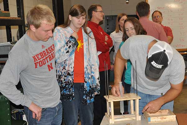 teammates Mitchell Maguire, Karissa Brehm and Julia Franck carefully observe while Justin Herting (right) makes and adjustment to the team's device during the Rapid Design Challenge.