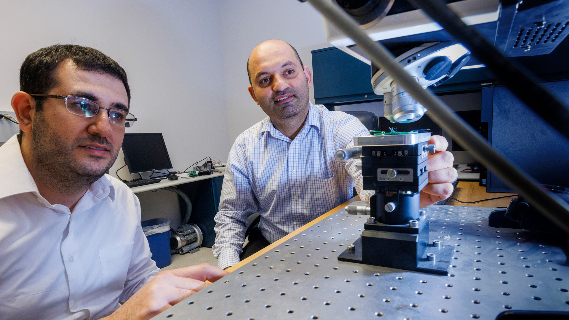 Fadi Alsaleem (right), assistant professor in The Durham School, and a graduate student explore the micro-electromechanical systems (MEMS) sensor with the use of a microscope. (Craig Chandler / University Communication)