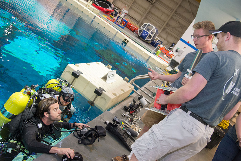 Nathan Borcyk and Brandon Jackson discuss how the gap spanner boom works with a diver who tested the prototype in June at the Neutral Buoyancy Laboratory's pool at the Johnson Space Center in Houston.