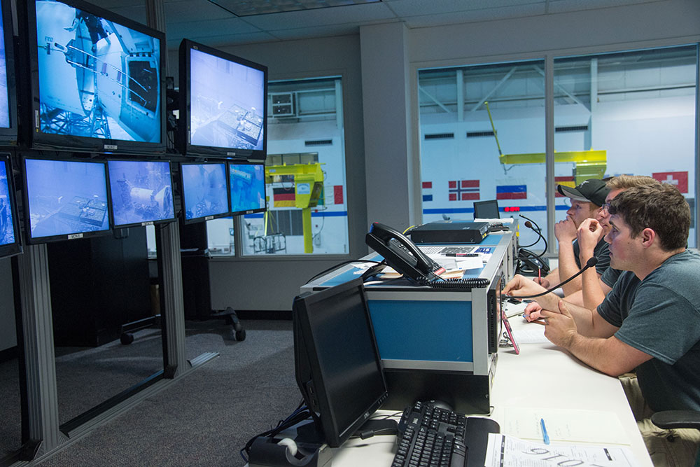 Members of the UNL Air and Space Research Team watch the test of their gap spanner boom from the control room and talk with divers conducting the test in the Neutral Buoyancy Laboratory's pool at the Johnson Space Center in Houston.