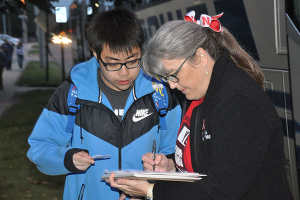 Lori Straatmann, director of advising, checks to see which motor coach a student is assigned to for the early morning Oct. 9 Industry Tour trip to Norfolk.