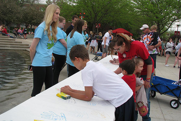 Participants in the Out of the Darkness Campus Walk on April 17 sign a memorial poster near Broyhill Fountain.