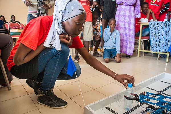 After her team's robot finishes a competition run, a student removes a water bottle from it's claw during the third day of the SenEcole robotics camp in Dakar, Senegal this past March.