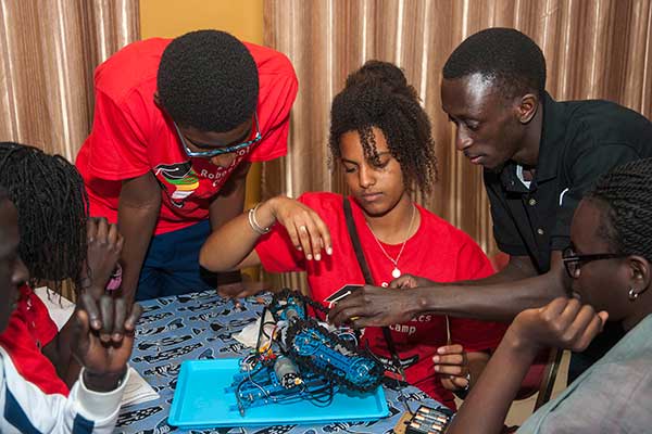 Sidy Ndao (right), assistant professor of mechanical and materials engineering, gives advice to a student team as it finishes assembling its robot at the SenEcole robotics camp in Dakar, Senegal this past March.