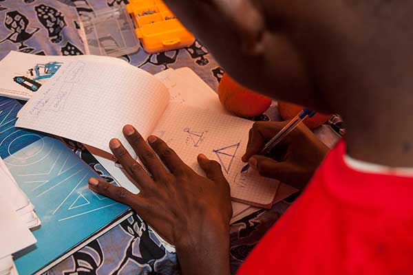 A student sketches out possible changes to his team's robot at the SenEcole robotics camp in Dakar, Senegal this past March.