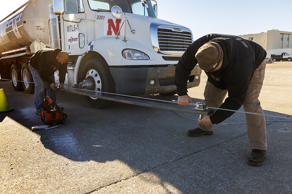 Midwest Roadside Safety Facility researchers connect cables that will allow two pickups to pull an 80,000-pound tractor-tanker truck to a speed of 50 mph.