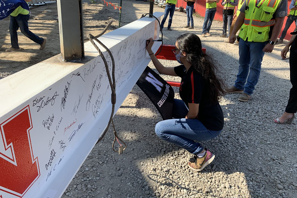 Luz Sotelo, a doctoral student in mechanical engineering, signs the steel beam before it is raised Wednesday during the Topping Out ceremony for Phase 1 of the college's construction project.