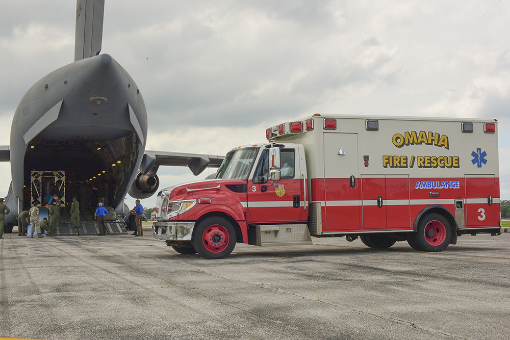 An Omaha Fire and Rescue ambulance sits near an Air Force cargo airplane at Offutt Air Force Base in Bellevue, Nebraska, during a 2018 simulated mission.