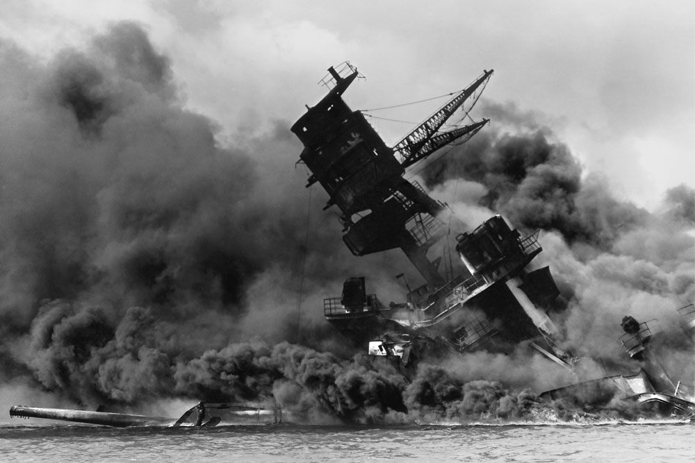 Shortly after being hit by a bomb dropped by a Japanese airplane, the USS Arizona burns in the water off the coast of Pearl Harbor.