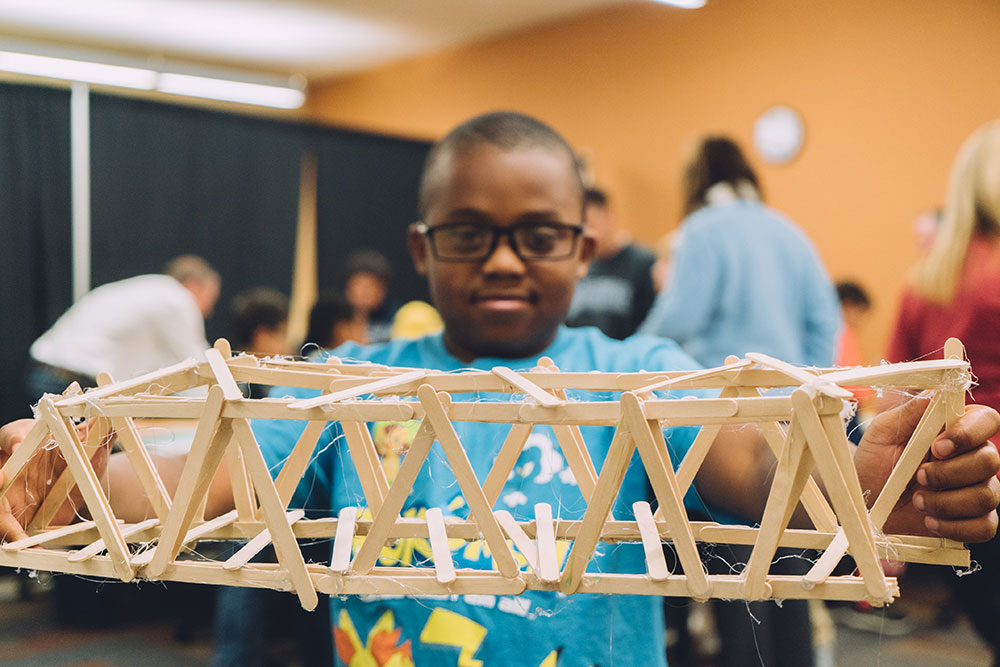A student shows off a completed bridge during the 