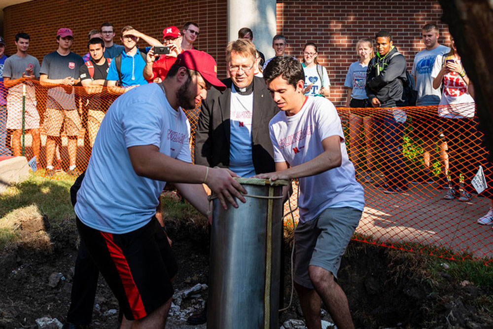 Father Bill Holoubek, a 1989 agricultural engineering alum, joins two members of the Engineering Student Advisory Board (eSAB) in pulling up the time capsule from the site where it had rested since being buried in 1987.