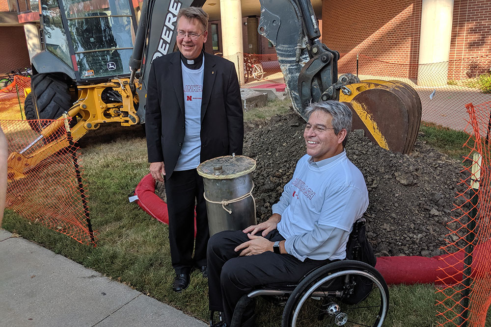 Father Bill Holoubek (left) and College of Engineering Dean Lance C. Pérez spend a moment with the time capsule before it was relocated to a temporary home.
