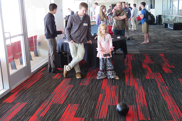 An electrical and computer engineering student helps a young visitor control the 2-1B Spheroid robot at the Senior Design Showcase on April 22 on the East Stadium Club Level of Memorial Stadium.