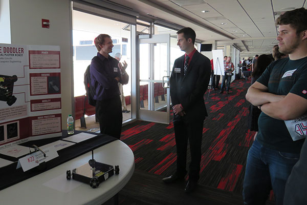 Alex Hinton (center) discusses the Salvadoodle Doodler with visitors to his team's booth at the Senior Design Showcase on April 22 on the East Stadium Club Level of Memorial Stadium.