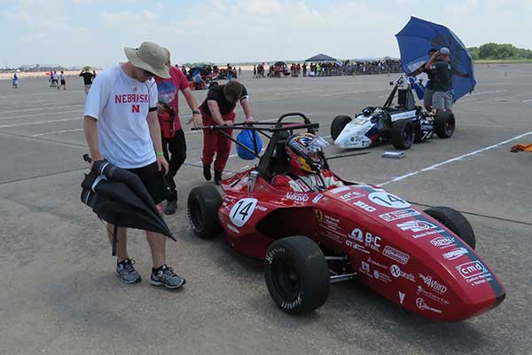 The crew pushes the Husker Motorsports Formula SAE car to the track before Friday's autocross run at Lincoln Airpark.