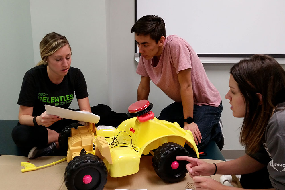 A Nebraska Engineering student (center) works with two UNMC physical therapy students on the renovation of a car at the Go Baby Go build Oct. 15.