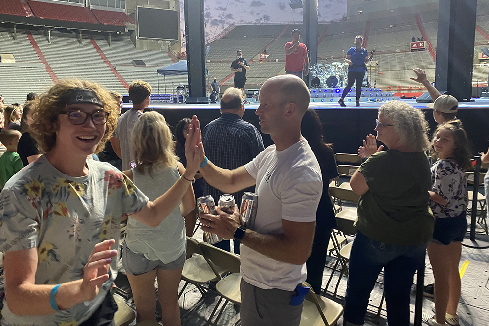 During the Aug. 13 soundcheck at Memorial Stadium, Carson Emeigh (left) reacts after being invited by Garth Brooks (on stage) to join the singer's crew to learn about the work of sound engineers at a live concert.