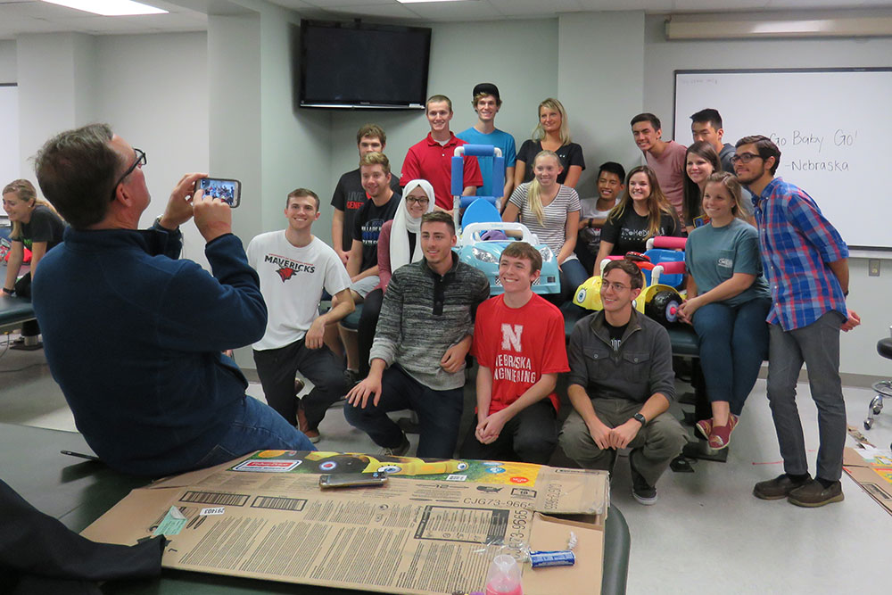 Jeffrey Woldstad, professor of biological systems engineering, takes a group photo of the Nebraska Engineering students who participated in the Oct. 15 Go Baby Go build and giveaway at the UNMC Student Life Center in Omaha.