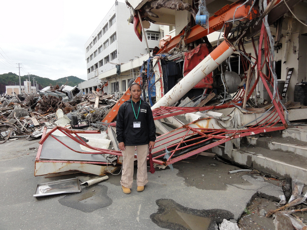 Norton stands in front of the canopy from a gas station, carried by tsunami waters and lodged into the entrance of a building