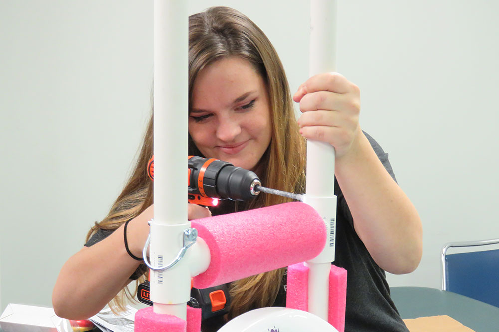 Anastasia Sanderson, a senior in biological systems engineering, drills a hole in PVC pipe during a renovation of a 