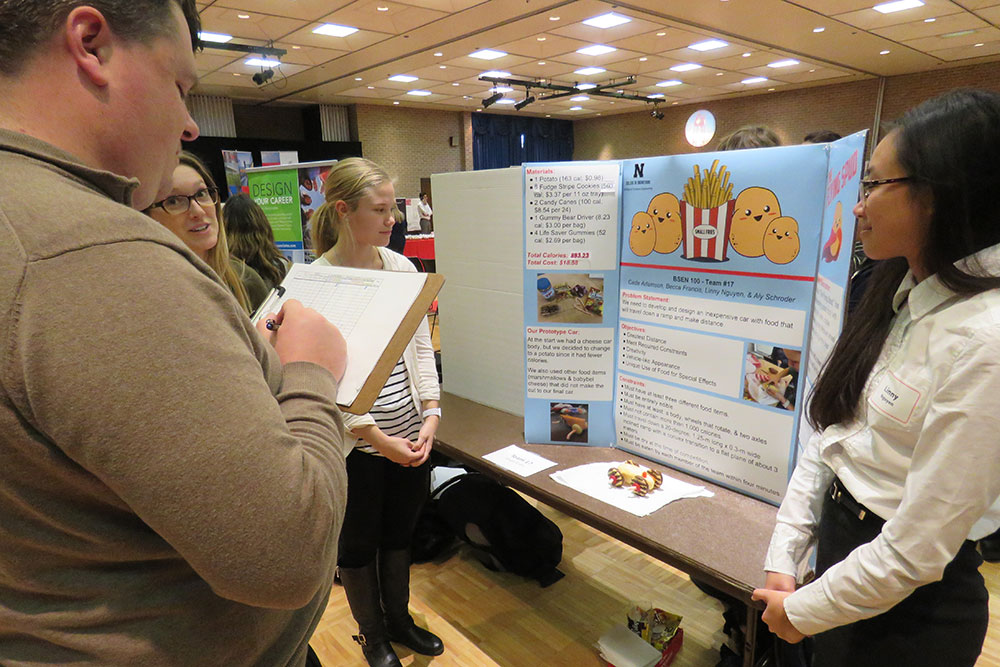 Becca Francis (left), Aly Schroeder and Linny Nguyen present their vehicle and poster to a judge during the Edible Vehicle competition on Dec. 5 at the Nebraska East Campus Union.
