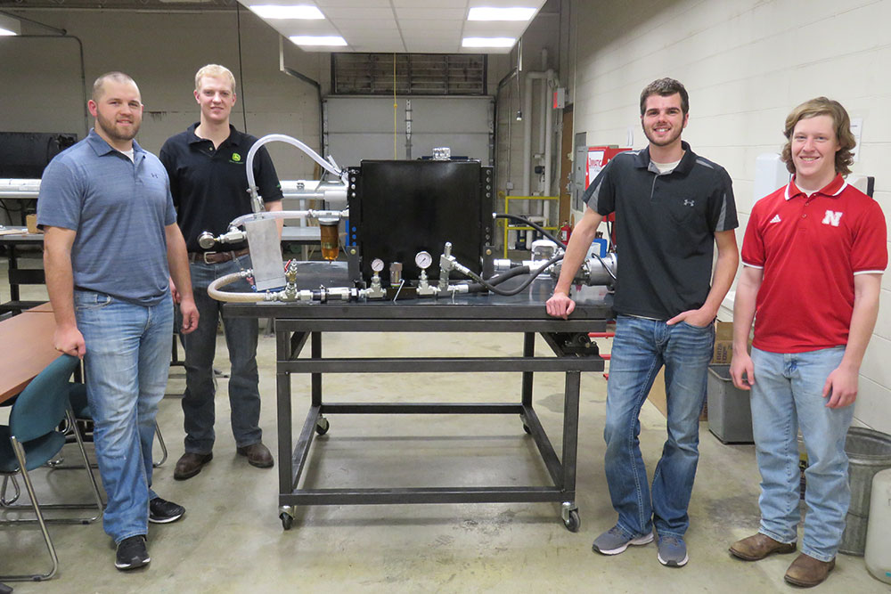 The biological systems engineering senior design capstone team -- (from left) John Nielsen, Luke Johnson, Aaron Steckly and Bennett Turner -- designed a system to help John Deere take damaging air bubbles out of the oil used in the hydraulic system of a tractor.