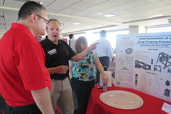 Mechanical and materials engineering student John Ebke explains his team's project - Semi-Automation of a Bung Torquing Process - to an interested guest April 22 at the Senior Design Showcase on the East Stadium Club Level of Memorial Stadium.