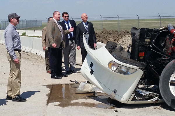 Nebraska Gov. Pete Ricketts (right) and Ron Faller, director of the Midwest Roadside Safety Facility, inspect the damage to the tractor-trailer's engine.