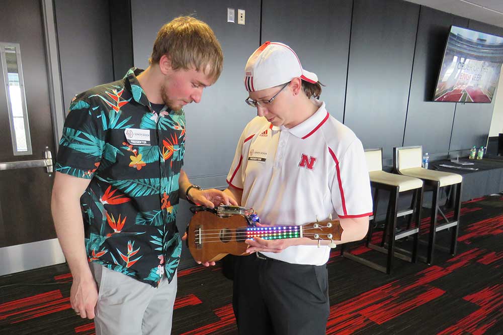 Zachary Kentner (left) and Andrew Tompkins examine the UkeBox, a device to teach people to play a ukulele, on April 21 at the Senior Design Showcase.